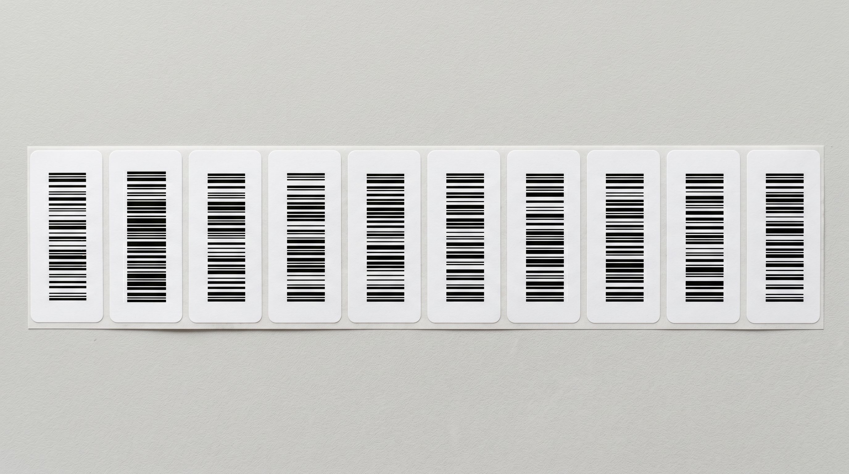 Close overhead view of retail product barcode labels aligned on a pale grey surface representing product data enrichment.