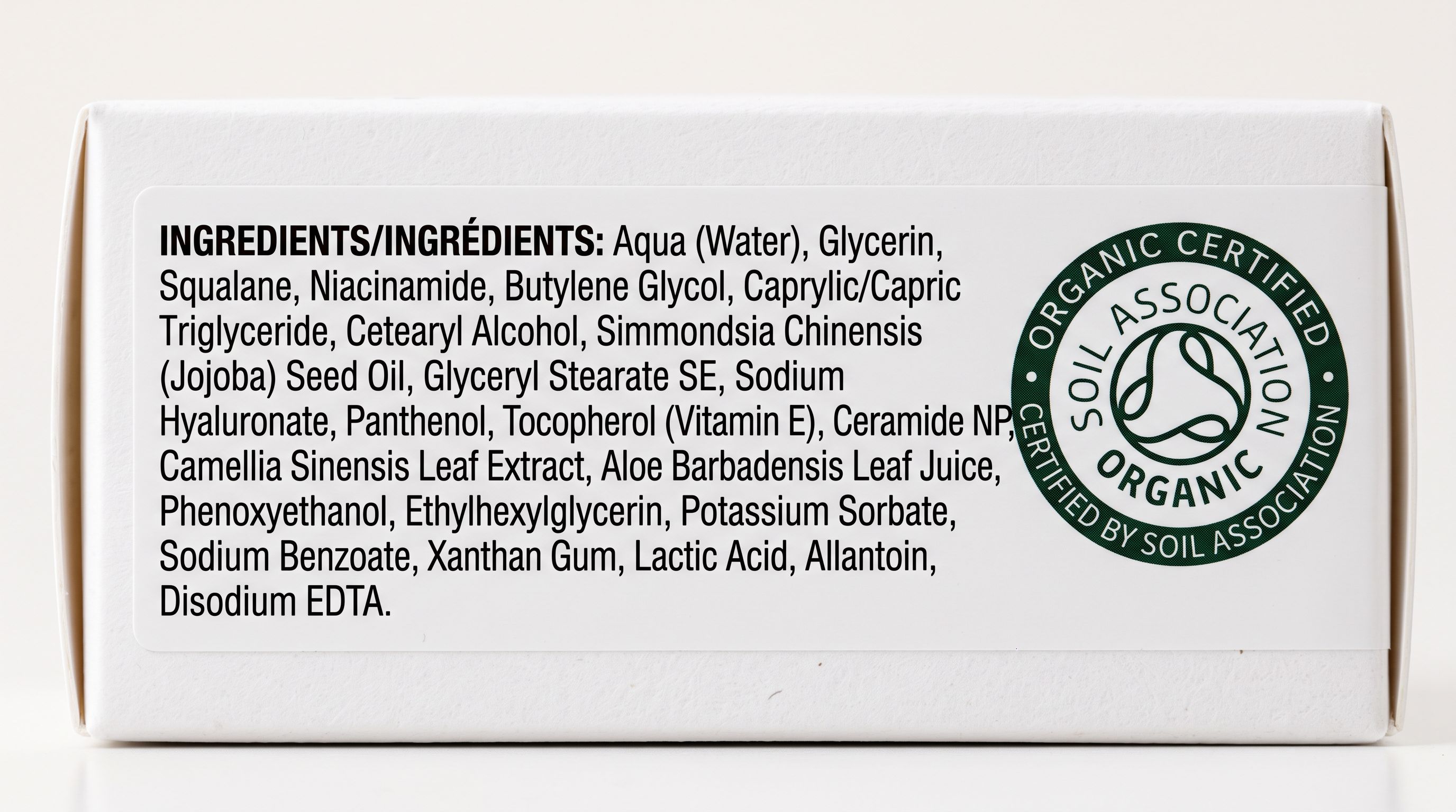 Cosmetic product label showing a printed INCI ingredient list in small text columns beside an official certification stamp on white packaging.
