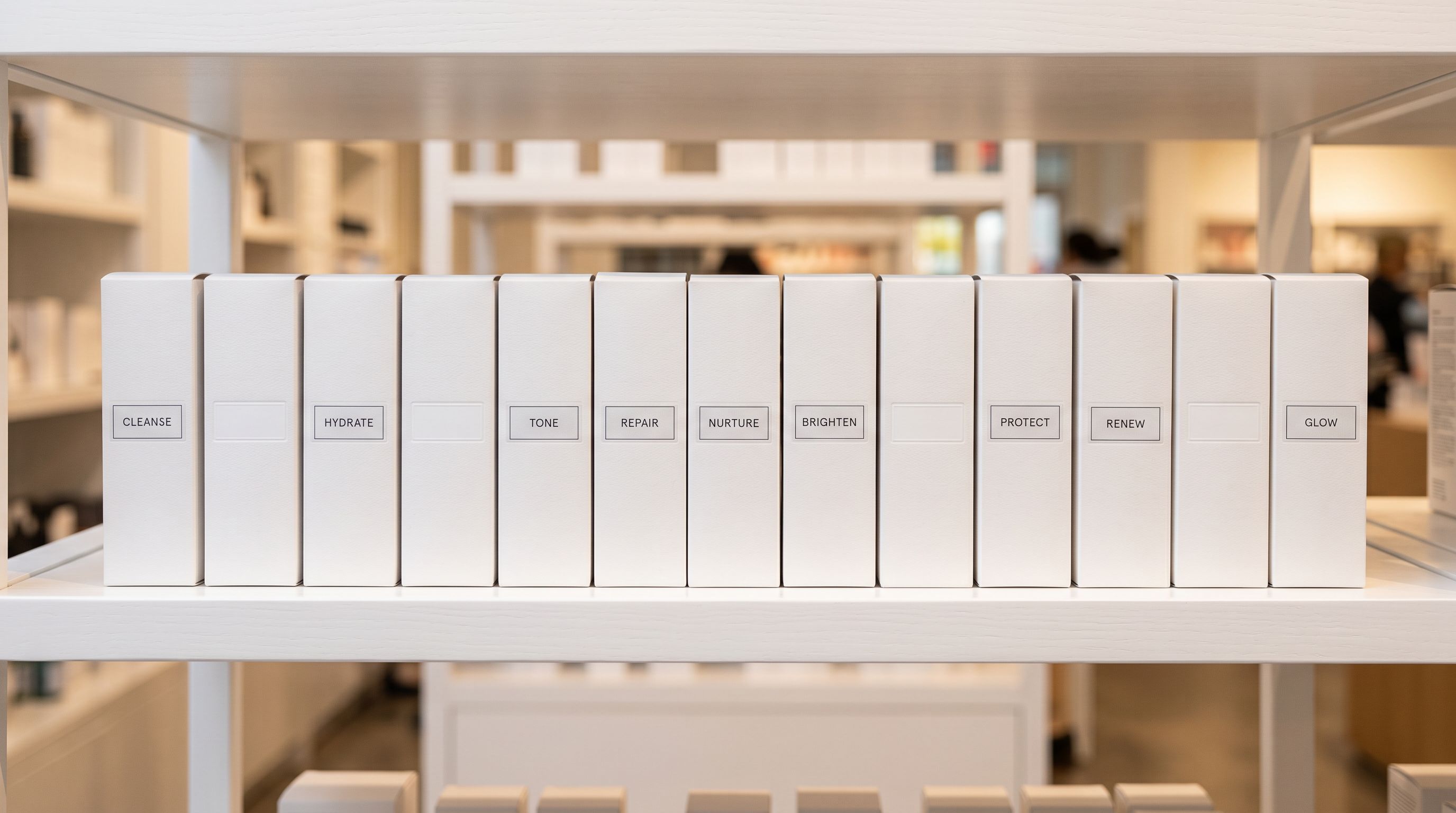 Row of identical product boxes arranged on white retail shelving, some with visible category labels and some with blank label holders, showing the difference between categorised and uncategorised products