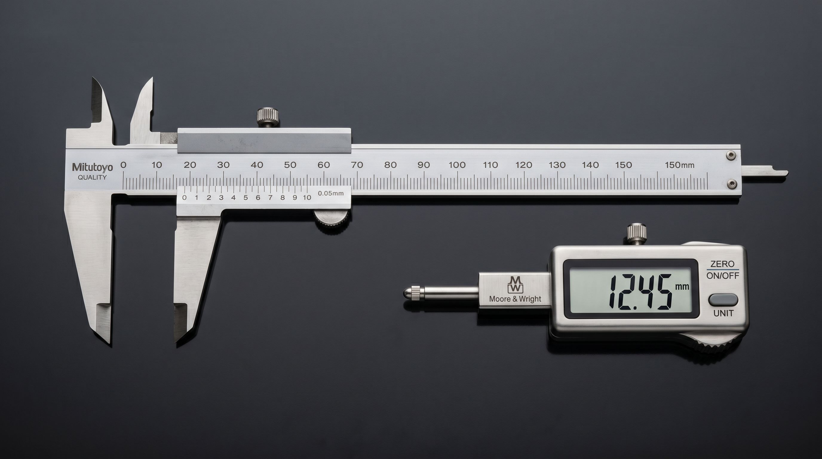 Precision stainless steel engineering calipers and measuring gauge on a polished dark workshop surface.