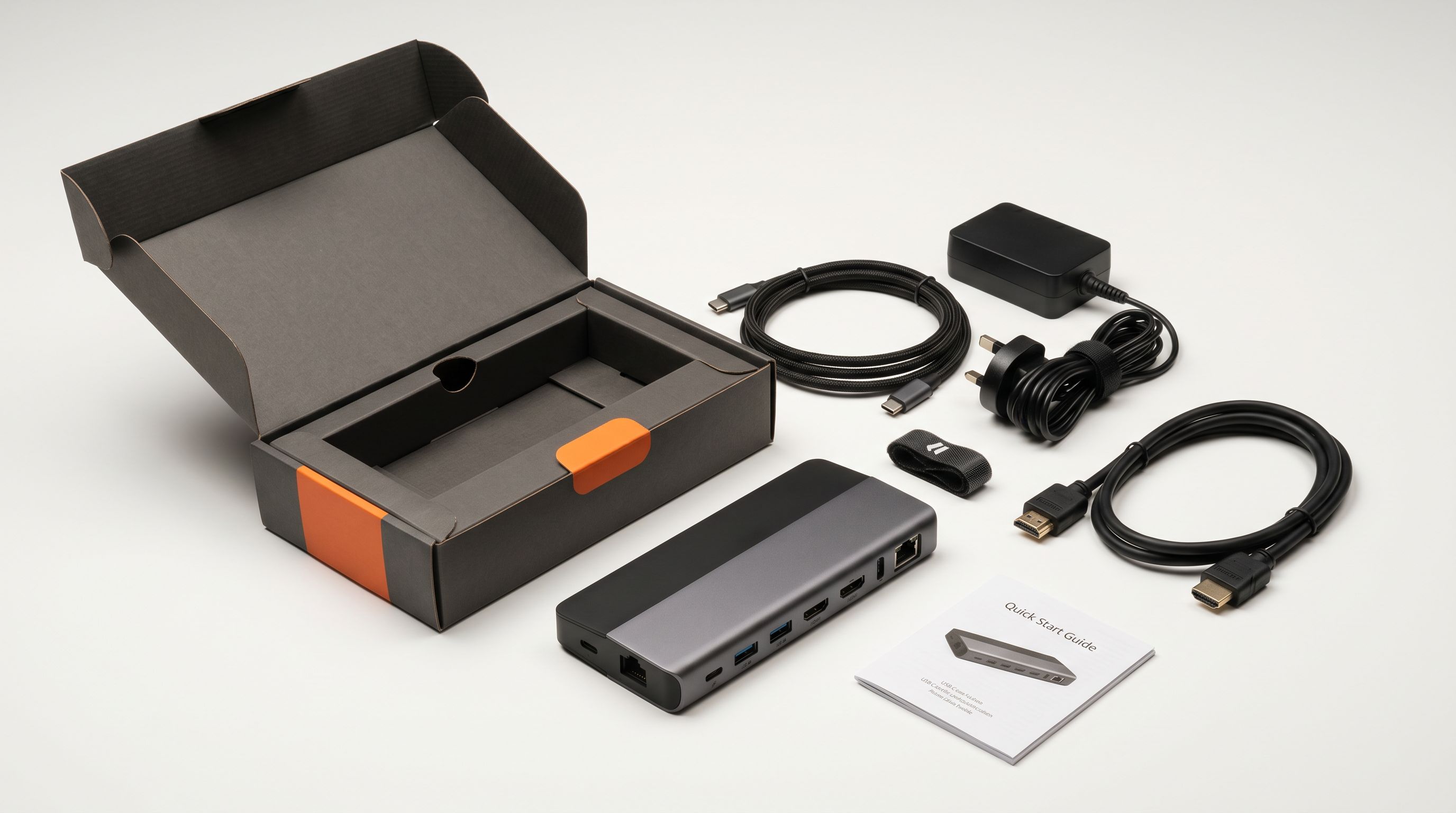 An electronics product box opened on a white surface showing contents including device cables adapters and documentation arranged around the main product.